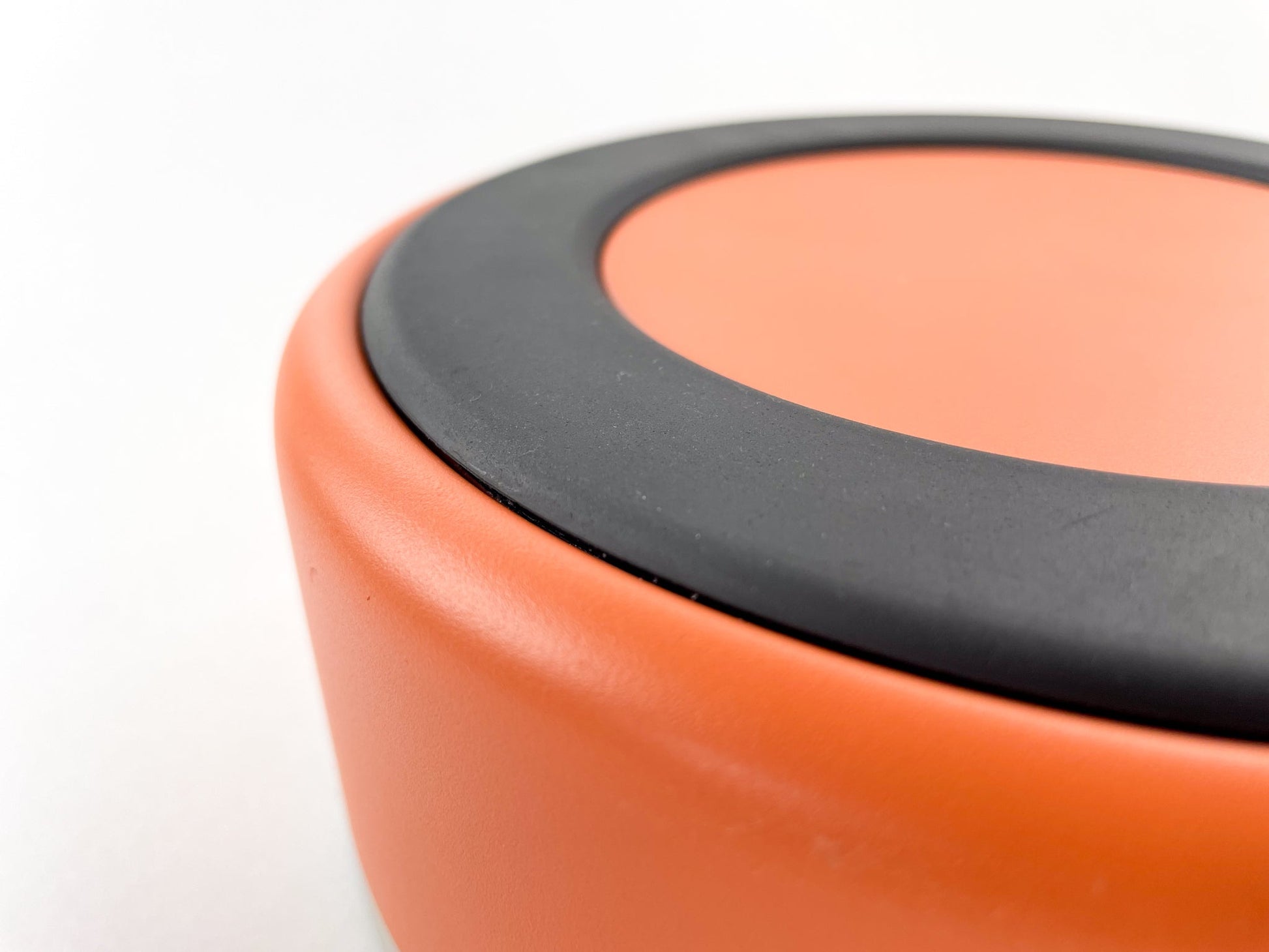 Detail of the anti slip rubber at the bottom of the stainless steel dog water bowl in rust colour. White background.