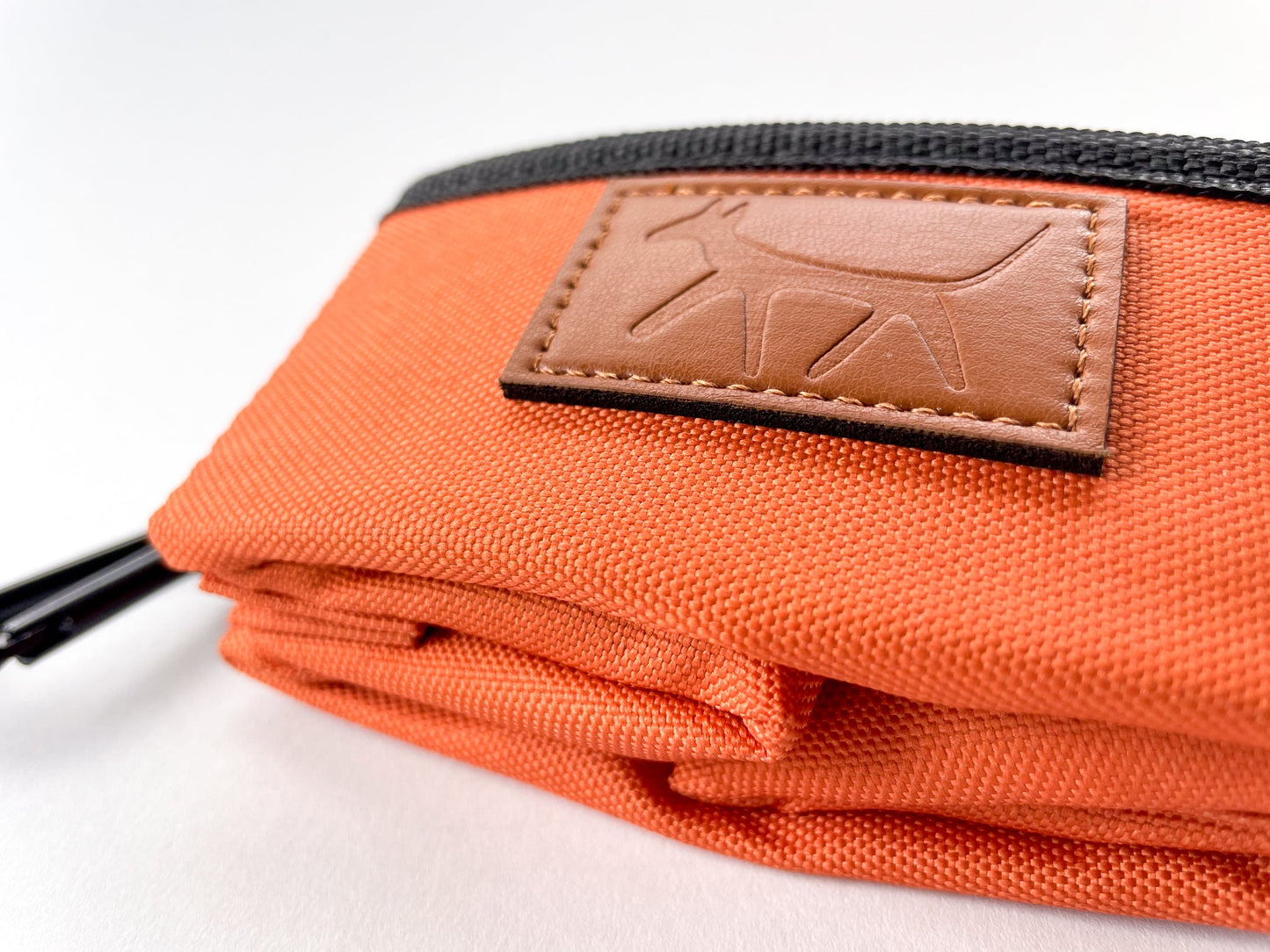 Detail of the leather Droggo logo on the dog travel bowl in rust colour.