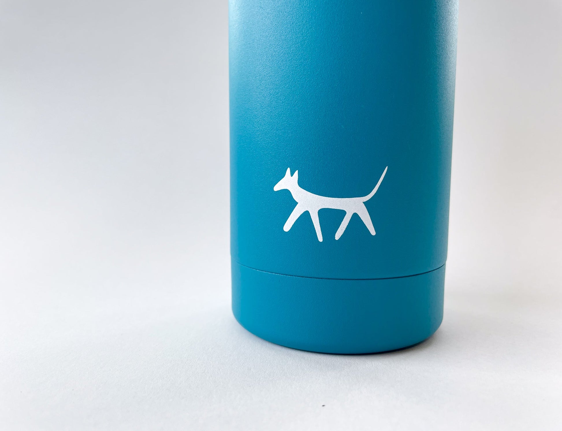 Detail of the Droggo logo in cream colour in front of the lake dog water bottle. White background.