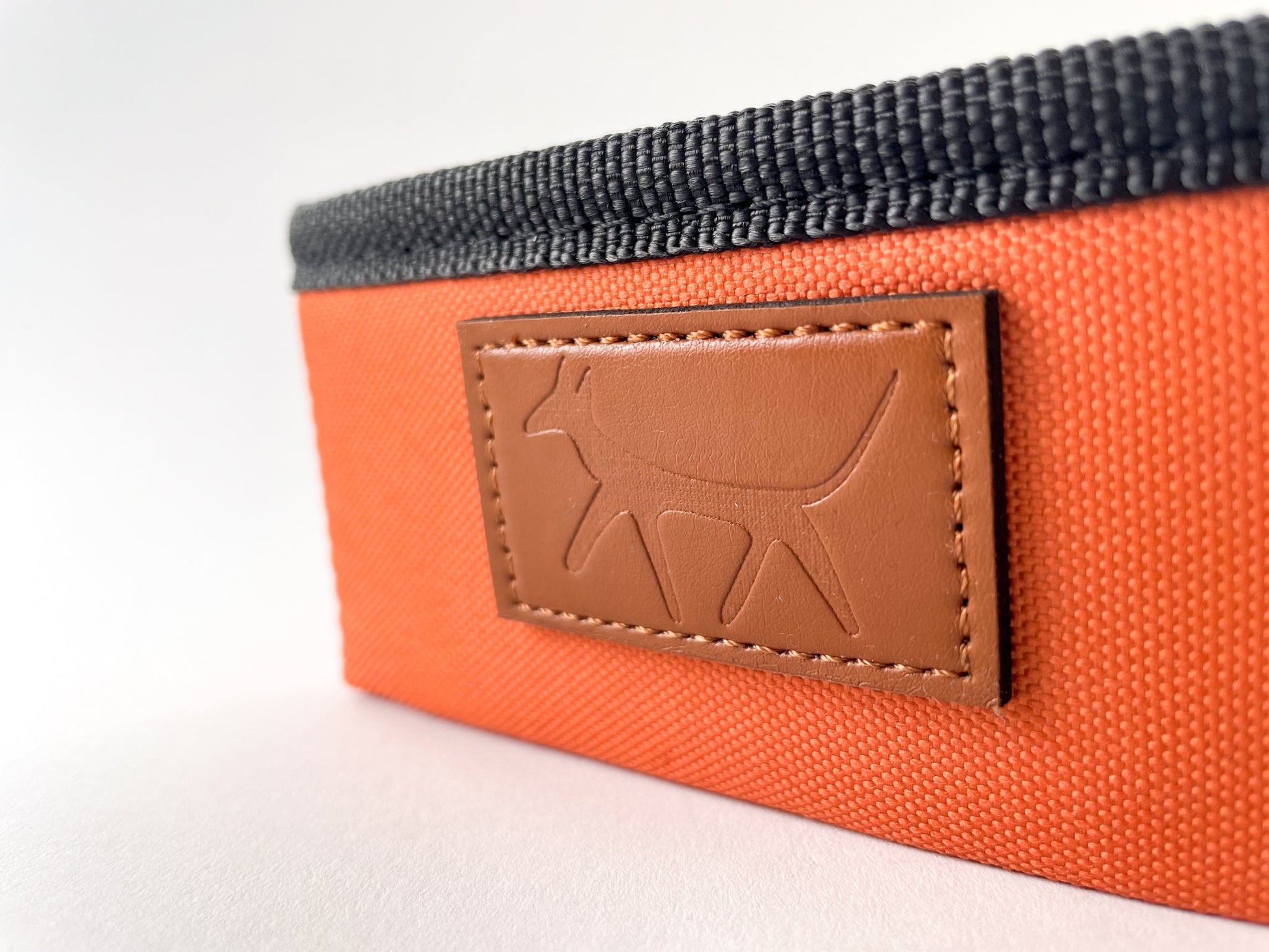 Detail of the leather Droggo logo on the dog travel bowl in rust colour.