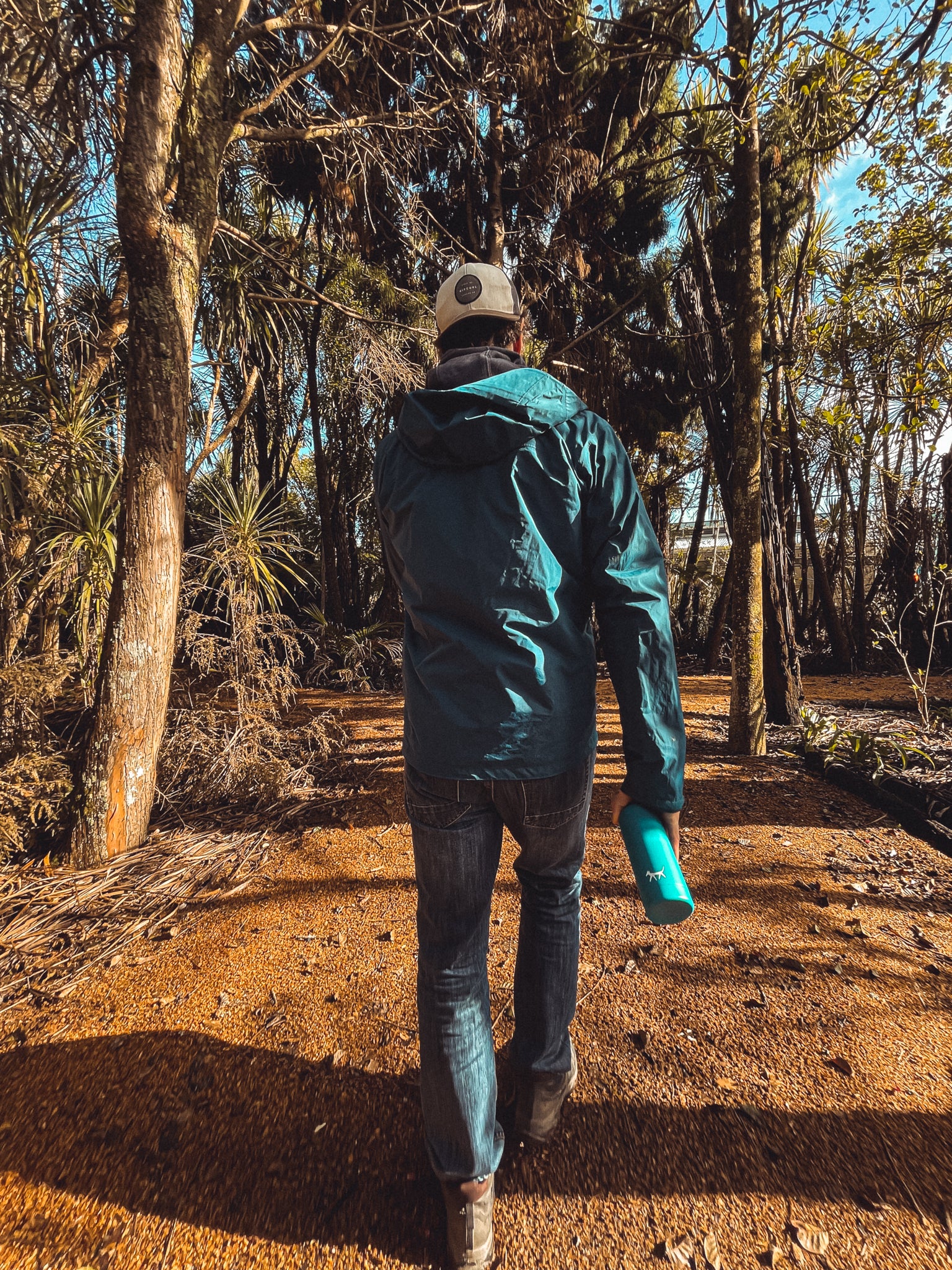 Man walking in a forest path holding a dog water bottle